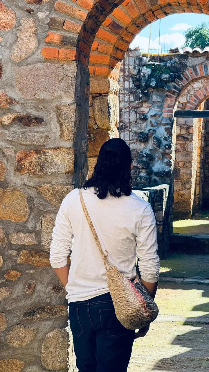 Praticante de costas atravessando arcos de pedra de ruínas antigas